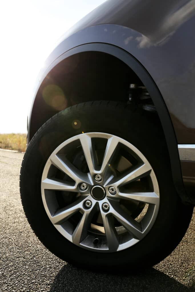 Roue à jante alliage à cinq doubles branches d'une voiture grise, vue au ras du sol