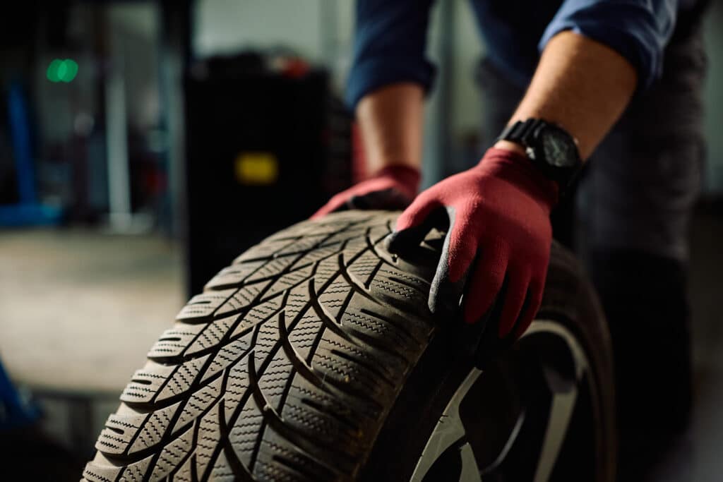 Technicien manipulant un pneu dans un garage