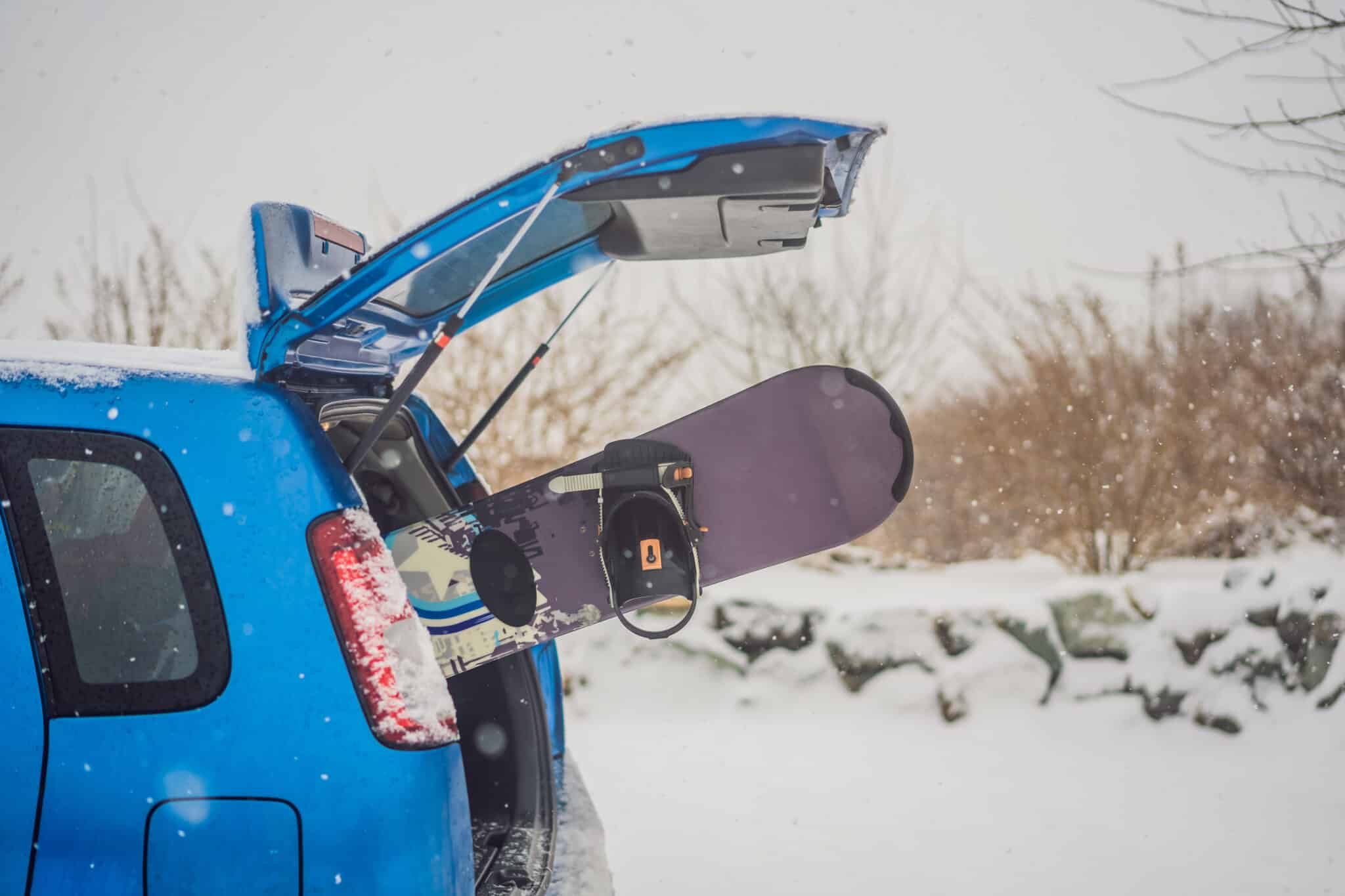 Voiture chargée avec coffre de toit sur une route de montagne enneigée