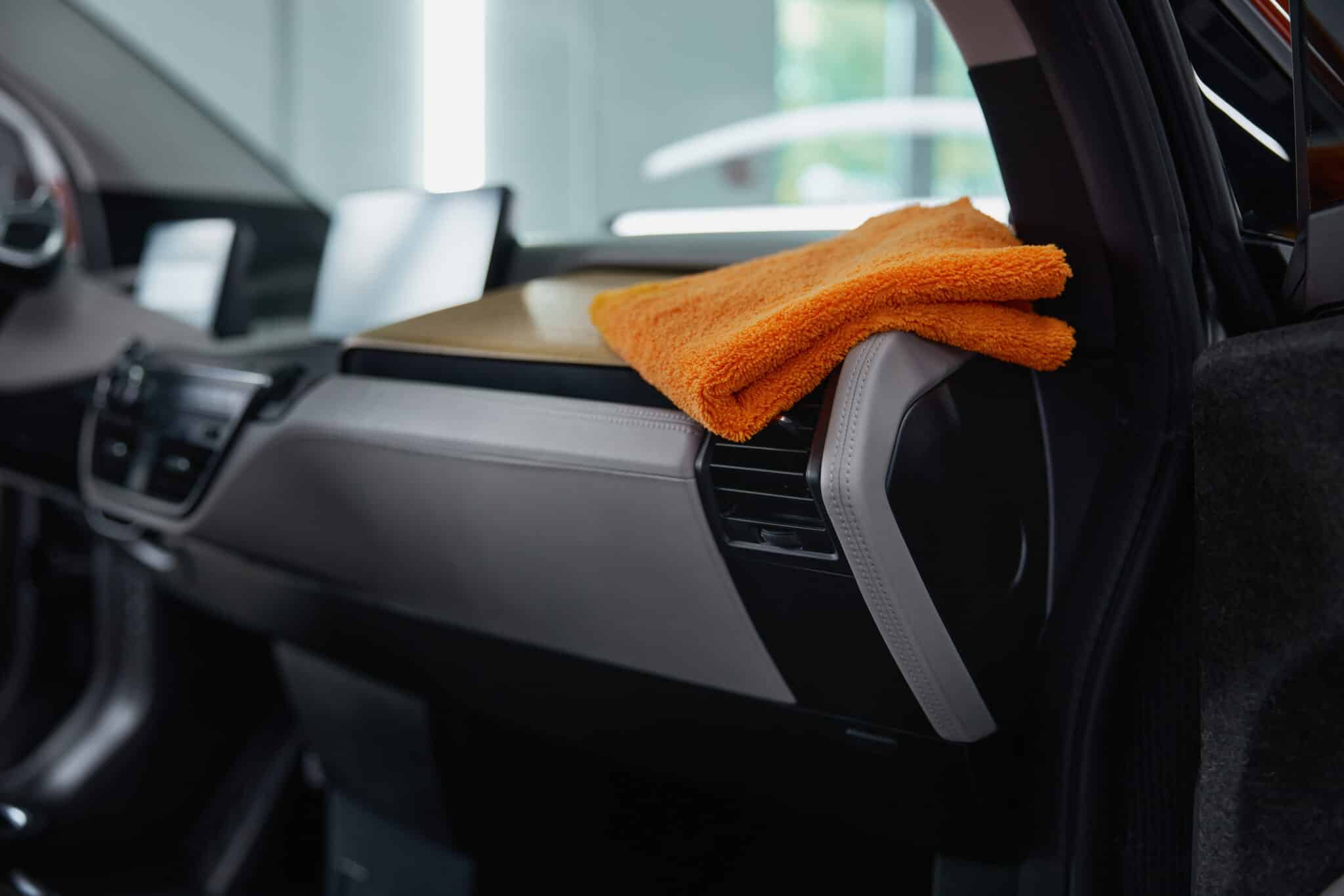 Microfibre orange posée sur la planche de bord d'une voiture, près d'une aération