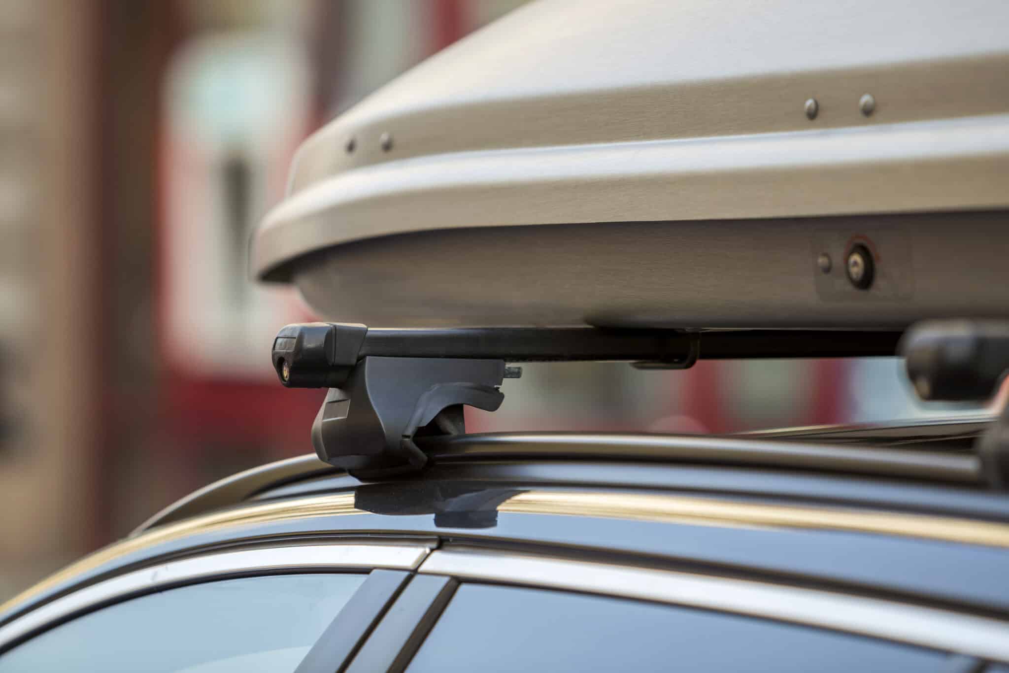 Coffre de toit gris fixé sur des barres transversales au-dessus d'une voiture