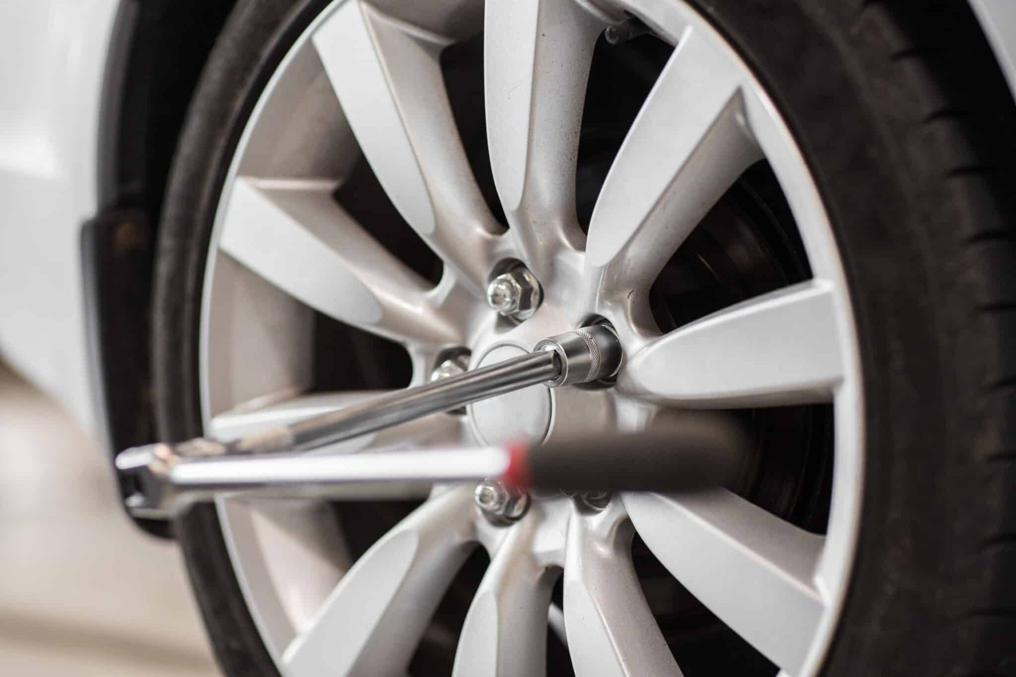 Clé avec rallonge engagée sur un écrou de roue d'une jante en alliage