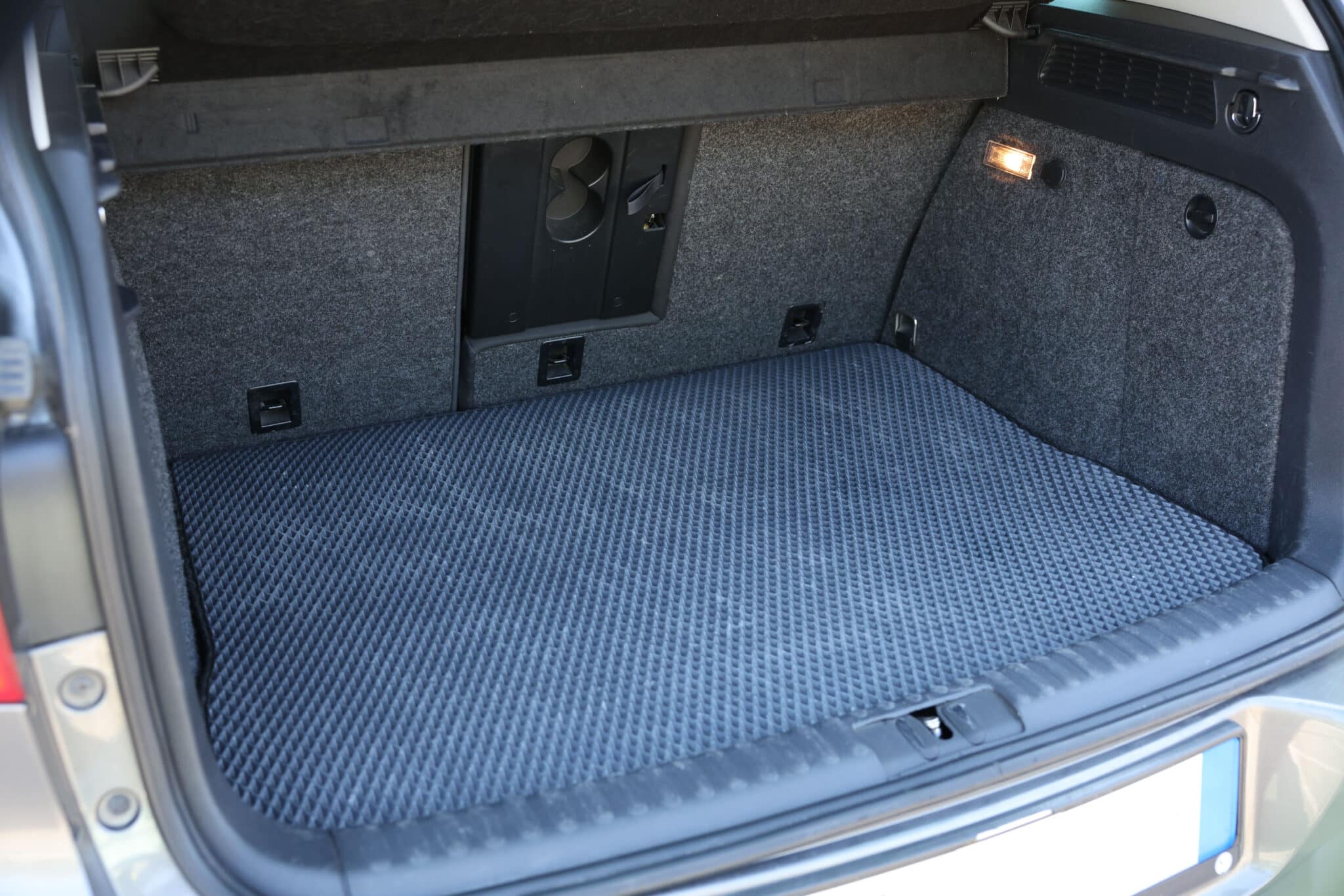 Coffre ouvert garni d'un tapis en caoutchouc gris à relief alvéolé, parois en moquette